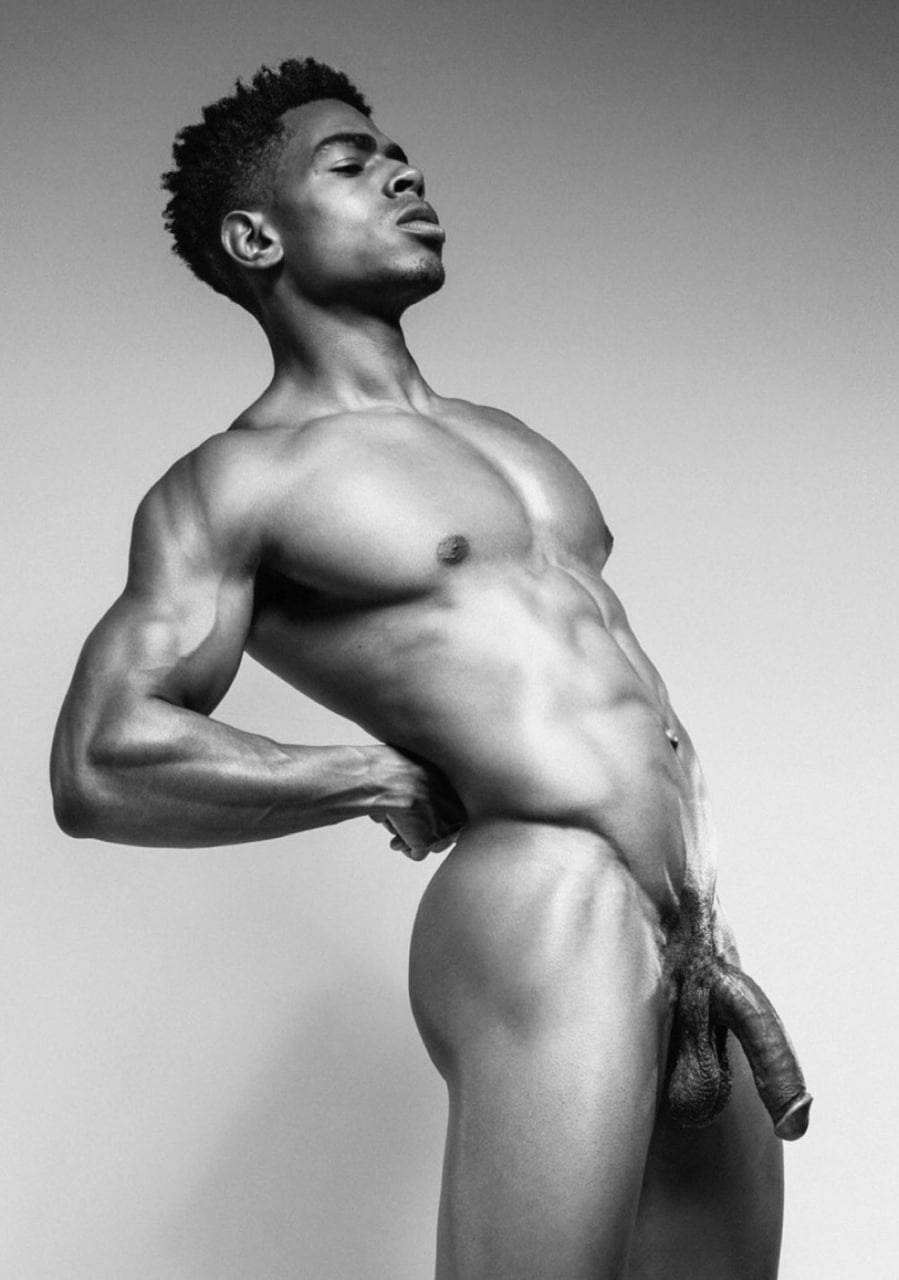 Nude muscular Black man posing in arched position with strong lighting, cock visible, black and white style